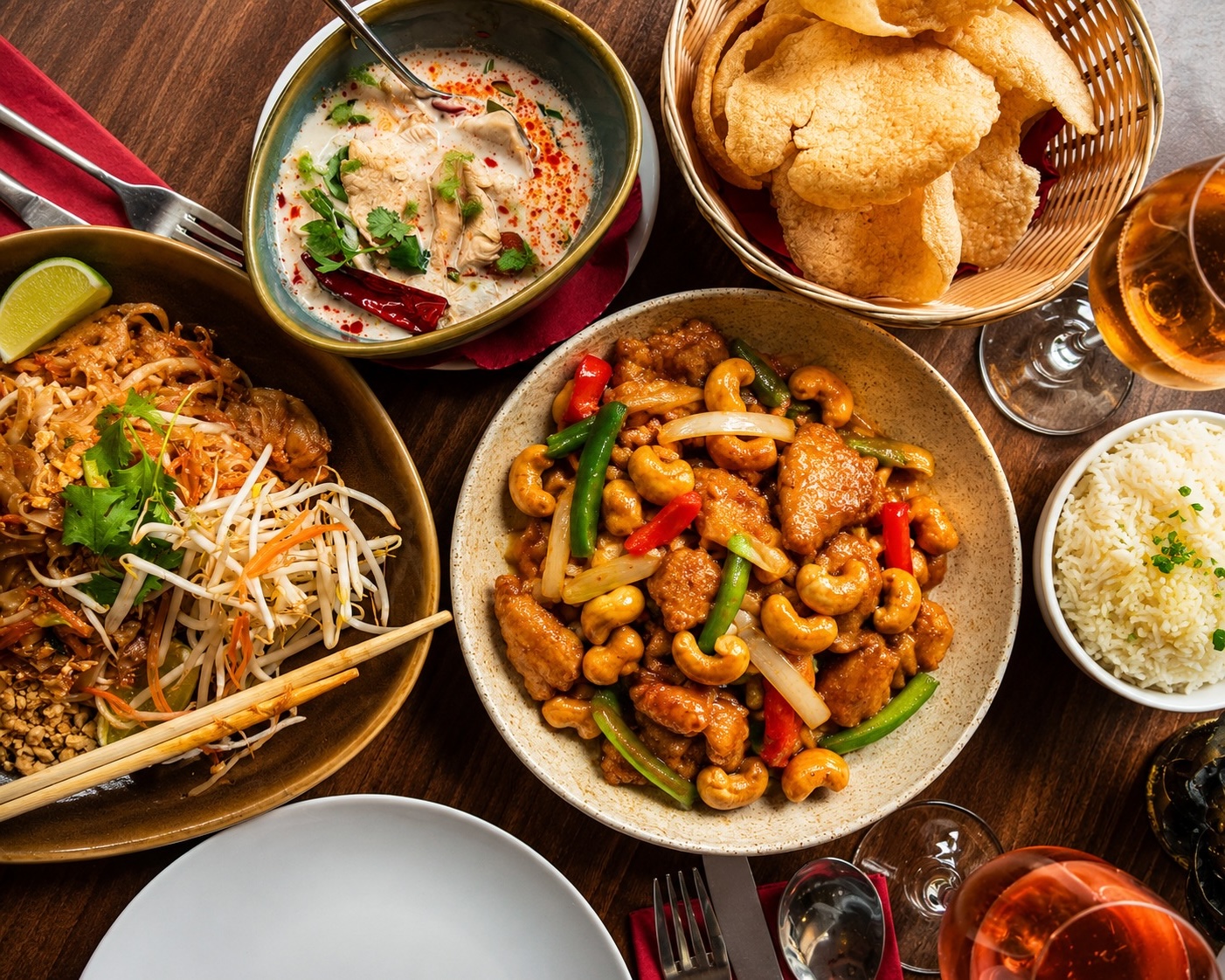 A spread of Thai dishes including pad thai, cashew chicken, tom kha soup and rice